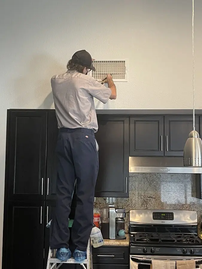 Technician inspecting an air vent during HVAC service in Clay